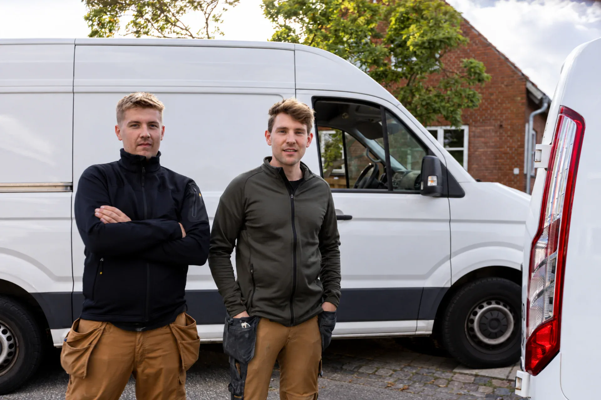 To mænd står foran en Wanding Works ApS varevogn i en boligområde.